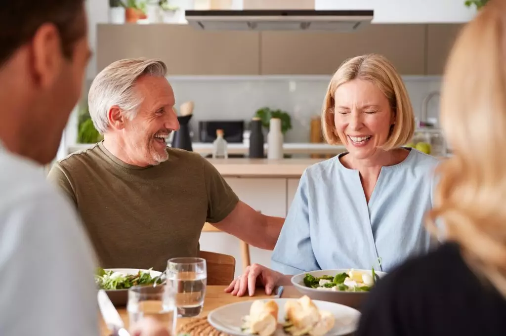 Famille avec des parents âgés et des enfants adultes mangeant ensemble un repas autour de la table à la maison